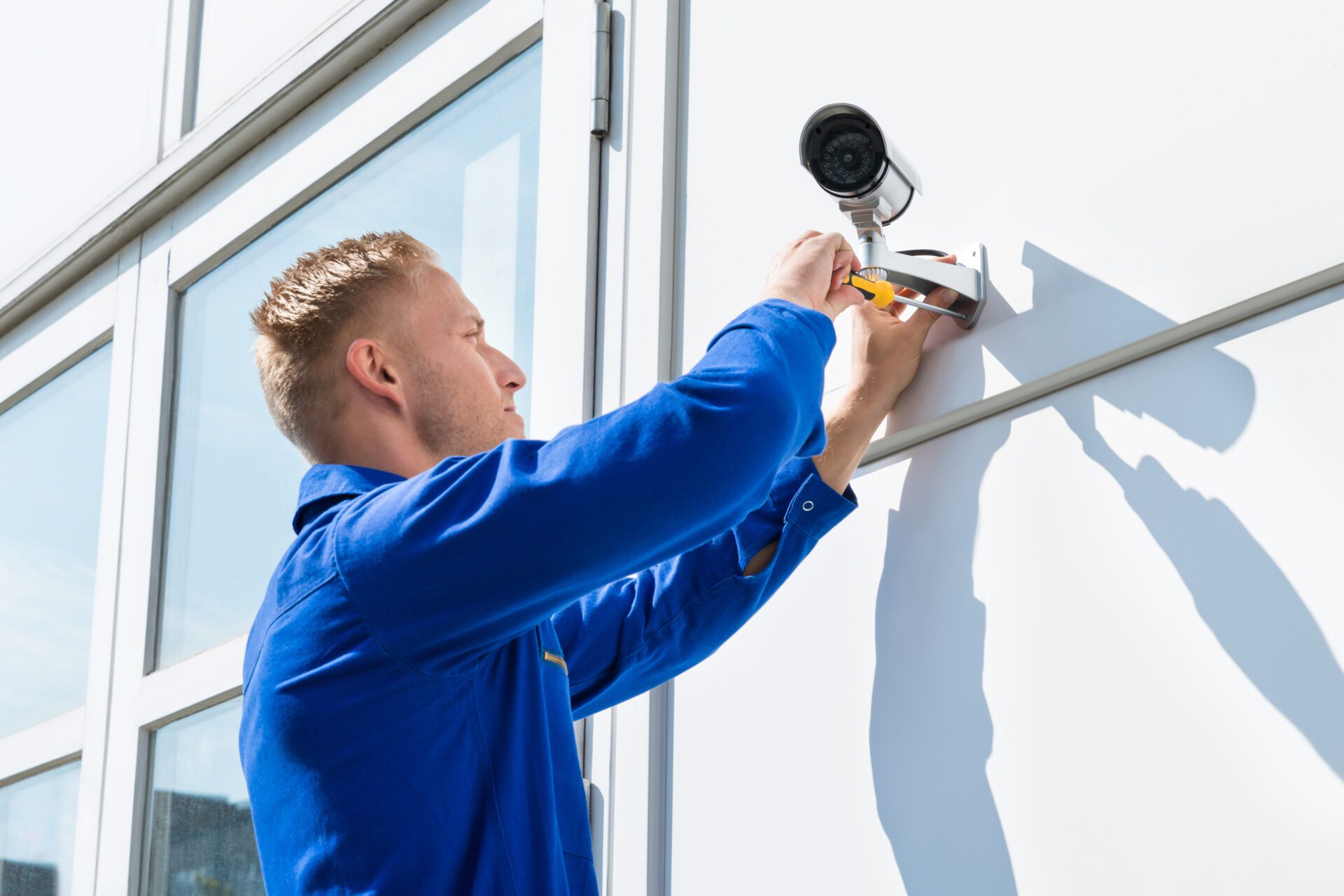 Technician,Fixing,Camera,On,Wall,With,Screwdriver